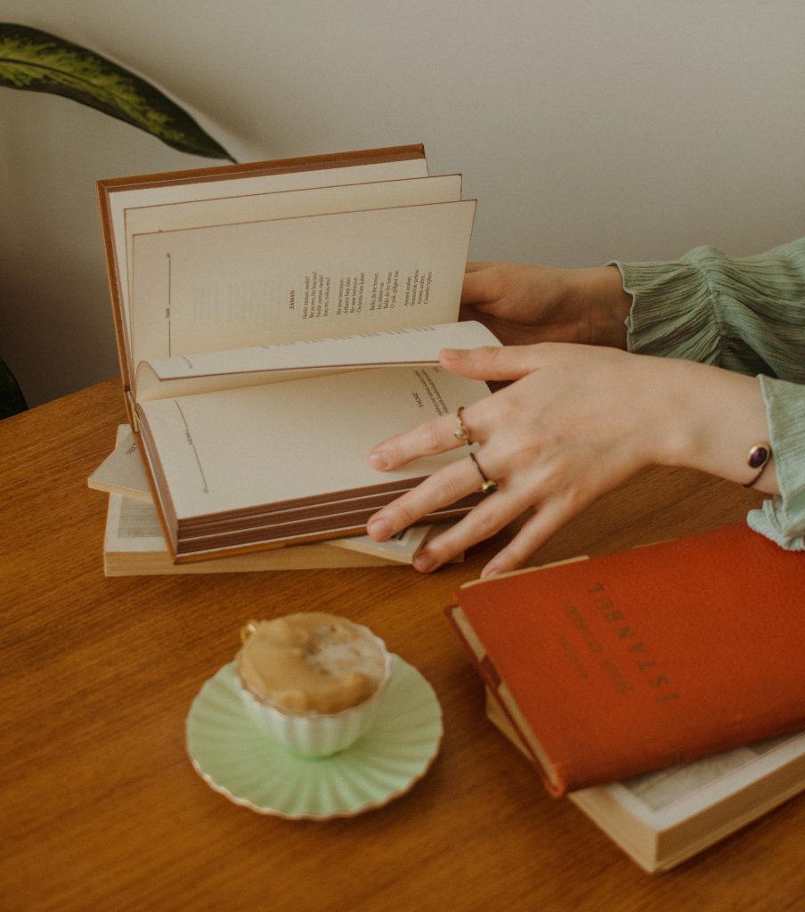 Frau mit Büchern am Schreibtisch. Foto: Pexels/Ekrulila
