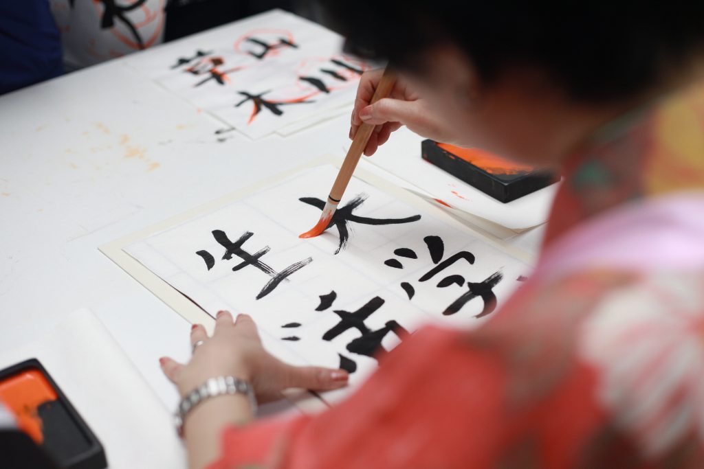 Eine Frau beim kunstvollen Gestalten von japanischen Schriftzeichen. Foto: Pexels, Engin Akyurt